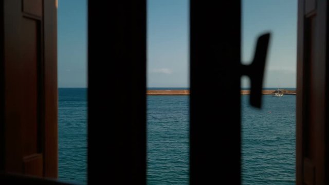 Inspirational shot of a window opening to a spectacular view of a Venetian lighthouse and the seafront of Chania, Crete, Greece