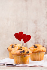 Homemade chocolate muffins with heart, vintage background.