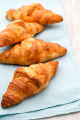 Tasty buttery croissants on old wooden table.