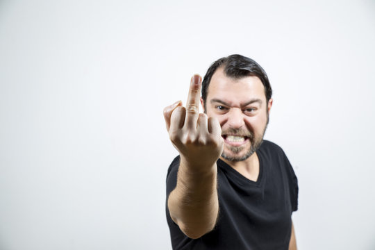 A bearded adult man is showing his middle finger as fuck you sign