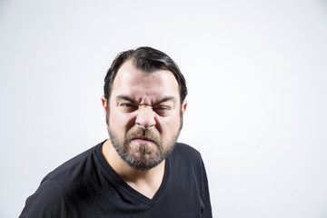 Adult man with frowning face is looking to the camera