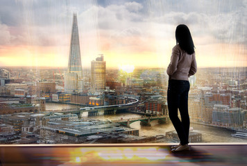 Young woman looking over the City of London at sunset. Future, new business opportunity and...