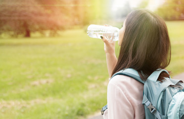 Woman drinking water outdoors in sunset in summer time