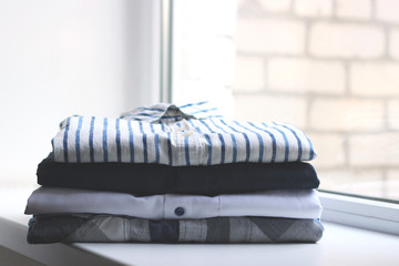 an ideal stack of clothes on the windowsill. minimalism. office clothes, shirts.