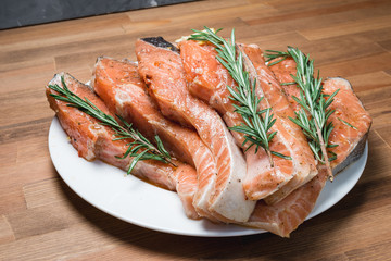 Raw salmon fillet with rosemary pepper thymus and salt on wooden cutting board