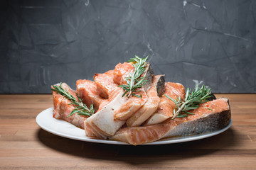 fresh raw red fish fillet on white plate and rosemary