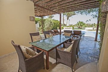 Swimming pool and outdoor dining area at at luxury tropical holiday villa resort