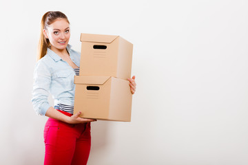 Woman moving into apartment house carrying boxes.