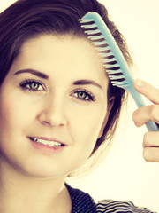 Woman brushing her long hair using comb