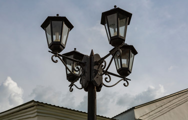 Fototapeta na wymiar Vintage iron lantern on a city street on a cloudy day 