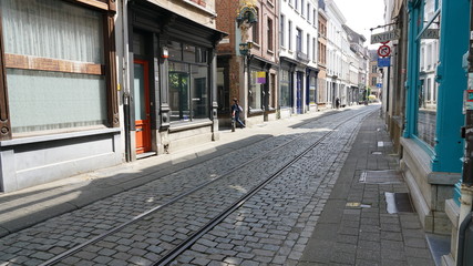 A quiet cobblestone street with tram rails and old houses in Antwerp, Belgium. 