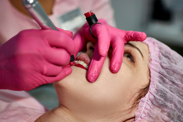 the master in the beauty salon makes a tattoo of the lips of the client