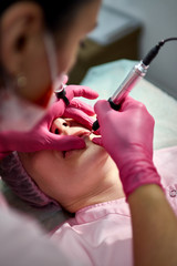 the master in the beauty salon makes a tattoo of the lips of the client
