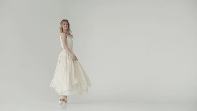 ballerina in a light studio dances in pointe shoes. ballet dancer in a light fluttering long dress