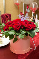 A huge bouquet of beautiful red roses in a box as a gift for parents. A bouquet of flowers for my mother. The inscription on the bouquet is To my beloved mother.
