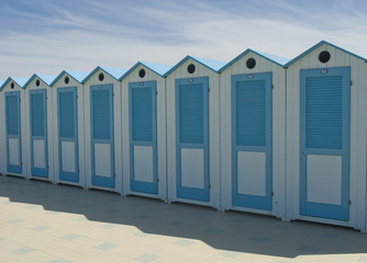 Naklejka premium wooden beach cabins by the sea, changing rooms, blue and white, used to change and put on bathing suit, vacation, summer, sun, ligurian riviera, Albenga beach, Italy