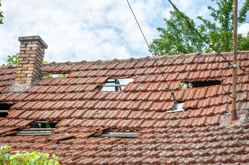 Collapsed roof with tiles on the old ruined and damaged domestic house after earthquake or hurricane storm close up