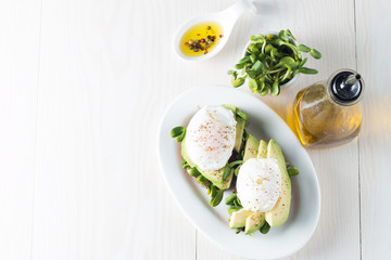 Avocado toast, cherry tomato on wooden background. Breakfast with toast avocado, vegetarian food, healthy diet concept. Healthy sandwich with avocado and poached eggs.