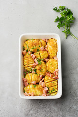 Baked potatoes with ham, herbs and breadcrumbs on gray light background. Scandinavian cuisine. Top view.