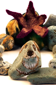 A dog with a sad look, painted on the surface of a stone, an artificial starfish of wool in the background.