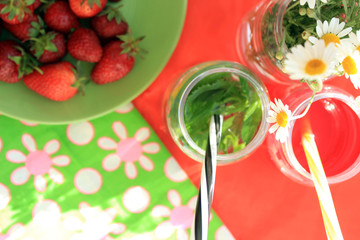 Summer flat lay with bright cocktails,  strawberry and camomile on red and green bright background