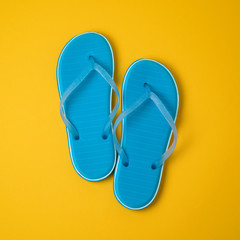 Blue flip flops over yellow background