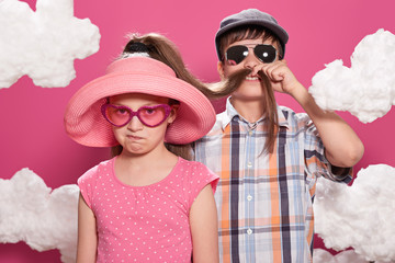 fashionable girl and boy posing on a pink background with clouds