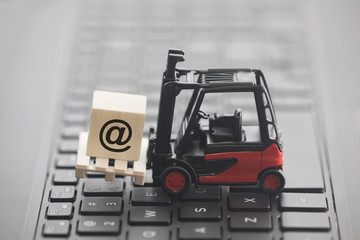 Forklift with email symbol on wooden block over laptop keyboard  © Jakub Krechowicz