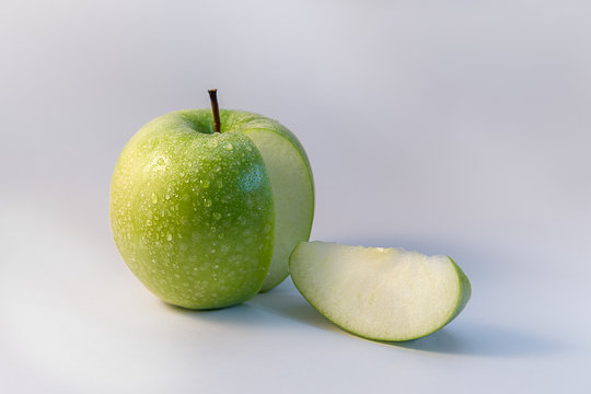 Green apple and one wedge of it isolated on white background