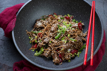 Stir-fried yakisoba with beef meat and vegetables in a wok pan, selective focus, horizontal shot