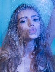 hairstyle of sexy woman in bodysuit in blue studio. hairstyle of pretty young woman with wet plastic sheet.
