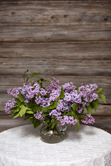 Bouquet of lilac in a glass vase./A bouquet of lilac on a white tablecloth table.