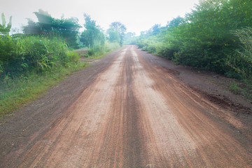 A long, straight dirt road disappears into the distant horizon.Light filters