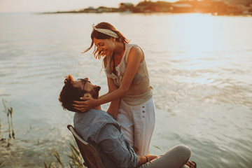 Young couple in love flirting by the river at sunset