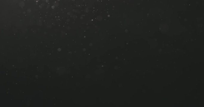 Slow motion dust particles floating over black background