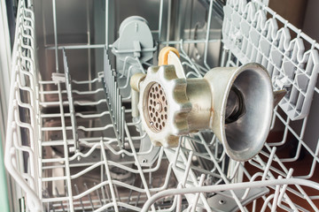 Hand grinder lies on the washing shelf in the dishwasher