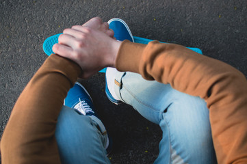 Top view of the modern hipster standing on the blue penny skateboard. The concept of modern culture, penny skateboarding, outdoor activity, modern lifestyle.