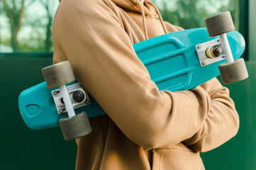 Side view of the young man holding his blue plastic penny board . The concept of modern culture,...