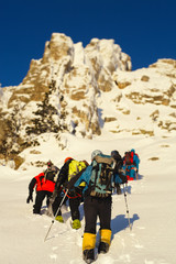 Climbers on the ascent to the background of snow-covered rocks. Tilt-shift effect.