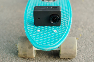 Action camera on the blue plastic penny skateboard. Front view. The concept of modern culture,...