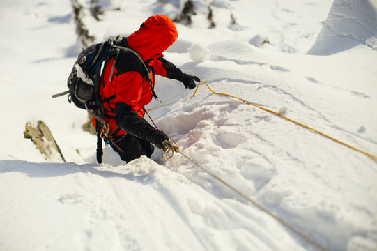 Mountaineer overcomes the complicated section on a snow-covered mountain slope.
