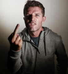 young arrogant and aggressive man giving middle finger in obscene and offending gesture with angry...