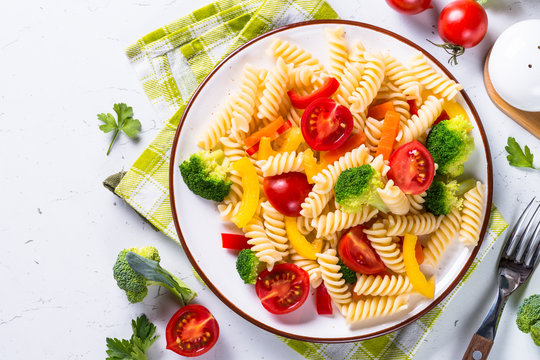 Vegan pasta fusilli with vegetables on white. 