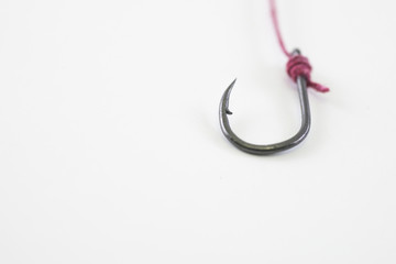 A single fishing hook hooked with red rope on a white background
