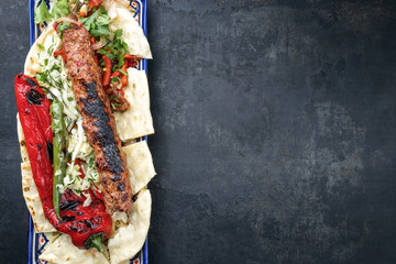 Traditionelles Adana Kebap mit Tomaten und Salat auf Fladenbrot mit Textfreiraum rechts