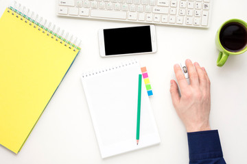 white desk, male hands, guy working at the computer, Cup of coffee, white smart phone lies on the desk,  office supplies,  white background with copy space, for advertisement, top view