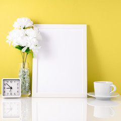 White frame, flower in vase, cup with tea or coffee, clock on wh