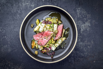 Modern barbecue dry aged sliced fillet steak with asparagus potato salad as top view on a plate