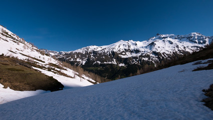 The Alps in springtime, sunny day snowy landscape ski resort, high mountain peaks in the alpine arch, avalanche danger.