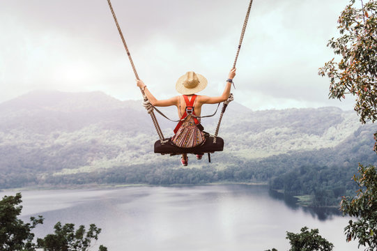 Carefree woman on the swing on a inspiring landscape.